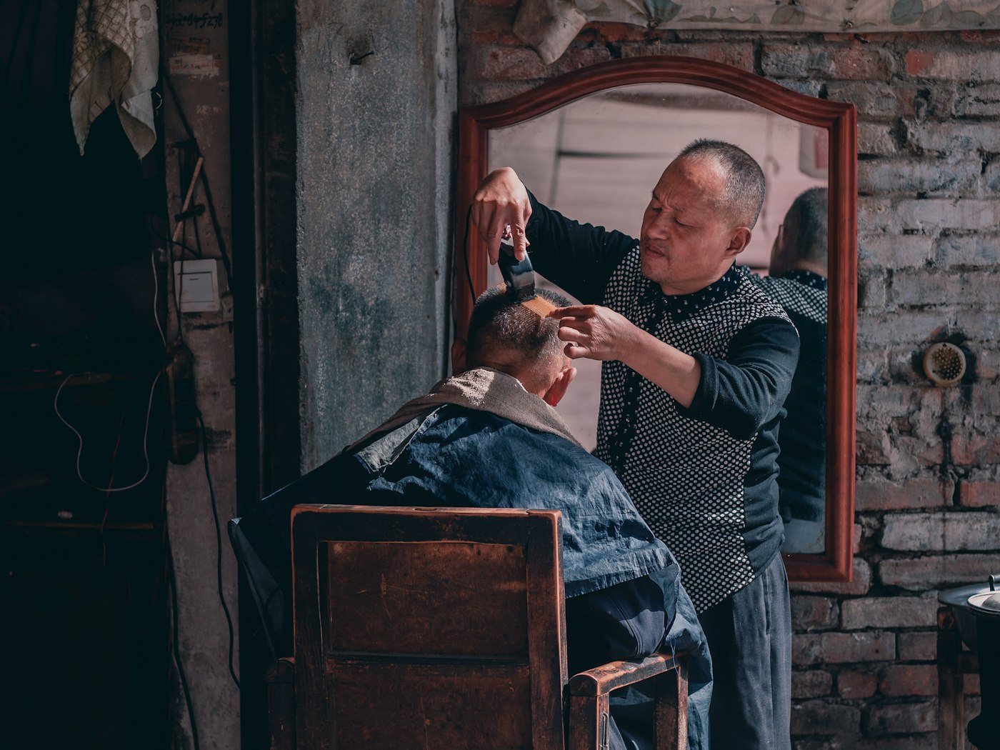 Barber trimming an older man's hair in a barbershop
