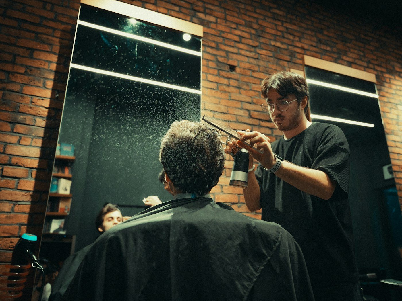 Barber cutting a customer's hair in a dimly lit barbershop